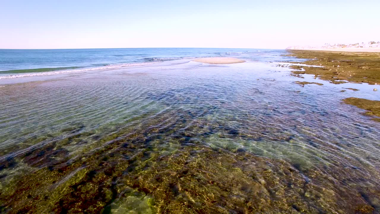 Aerial low long angle of the tide going out in Rocky Point, Mexico