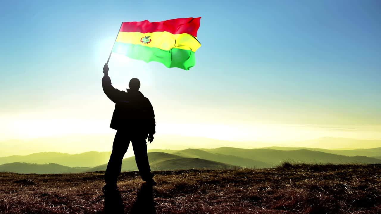 Successful silhouette man winner waving Bolivia flag on top of the mountain peak. Cinemagraph LOOP background