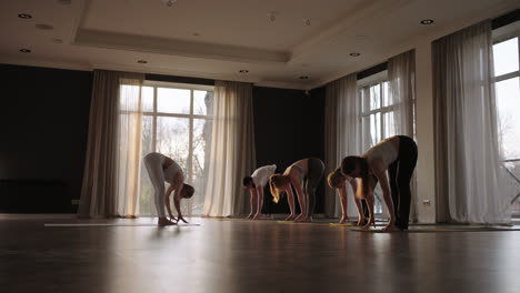 In-slow-motion-a-joint-female-Pilates-workout-with-an-instructor-shows-thin-and-plump-women-in-the-gym-in-the-morning-in-the-sun.-The-glare-of-the-sun-on-the-floor