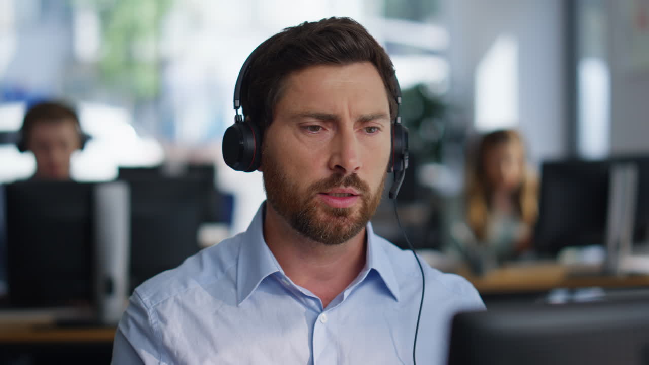 Serious helpdesk assistant talking headset in office coworking space closeup