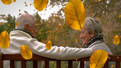 animation of orange autumn leaves falling over happy senior caucasian couple in park