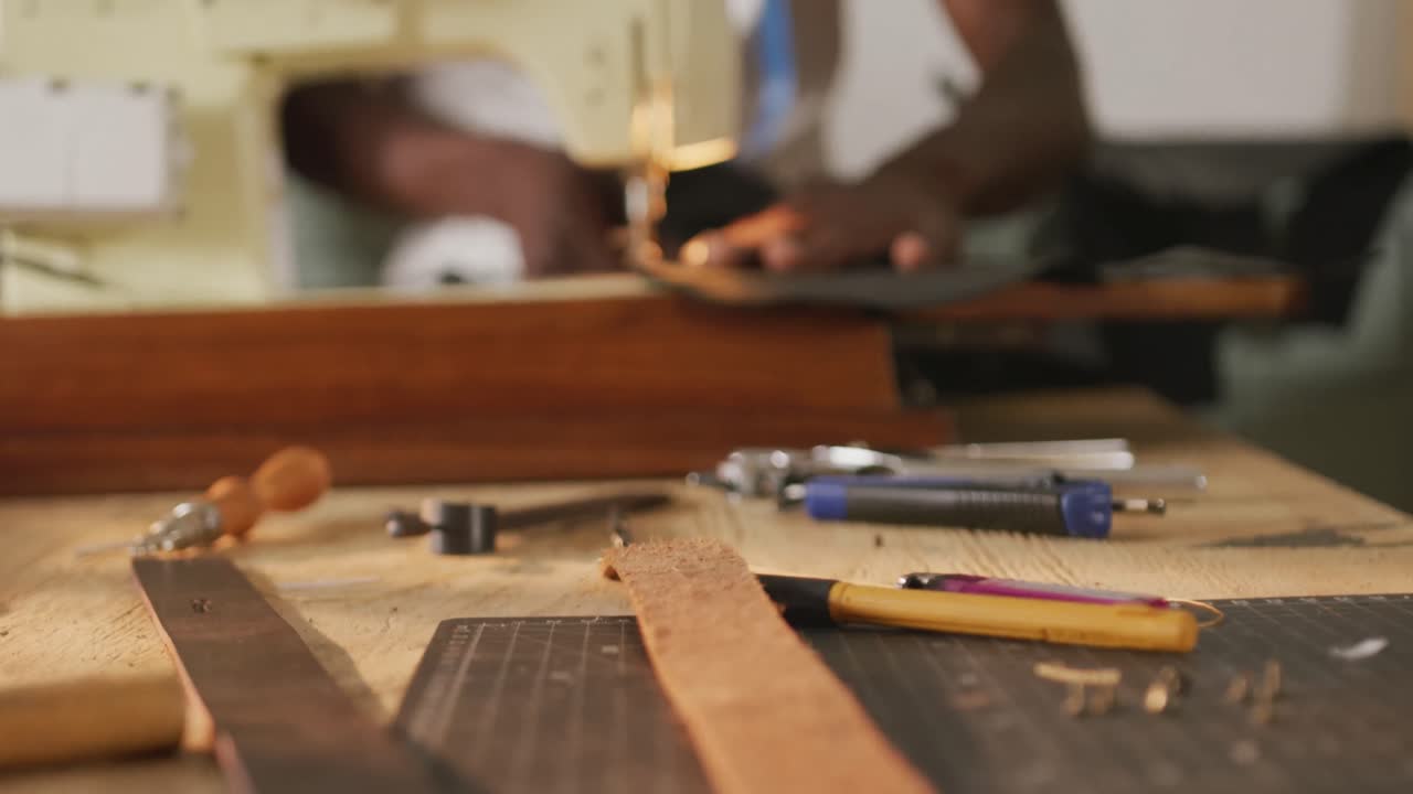 Hands of african american craftsman sewing leather in leather workshop