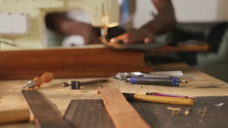 hands of african american craftsman sewing leather in leather workshop