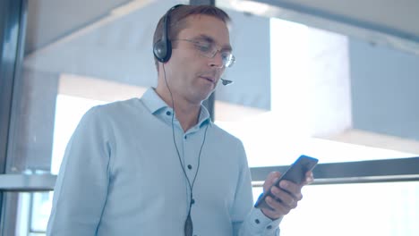 serious male professional in headset holding mobile phone