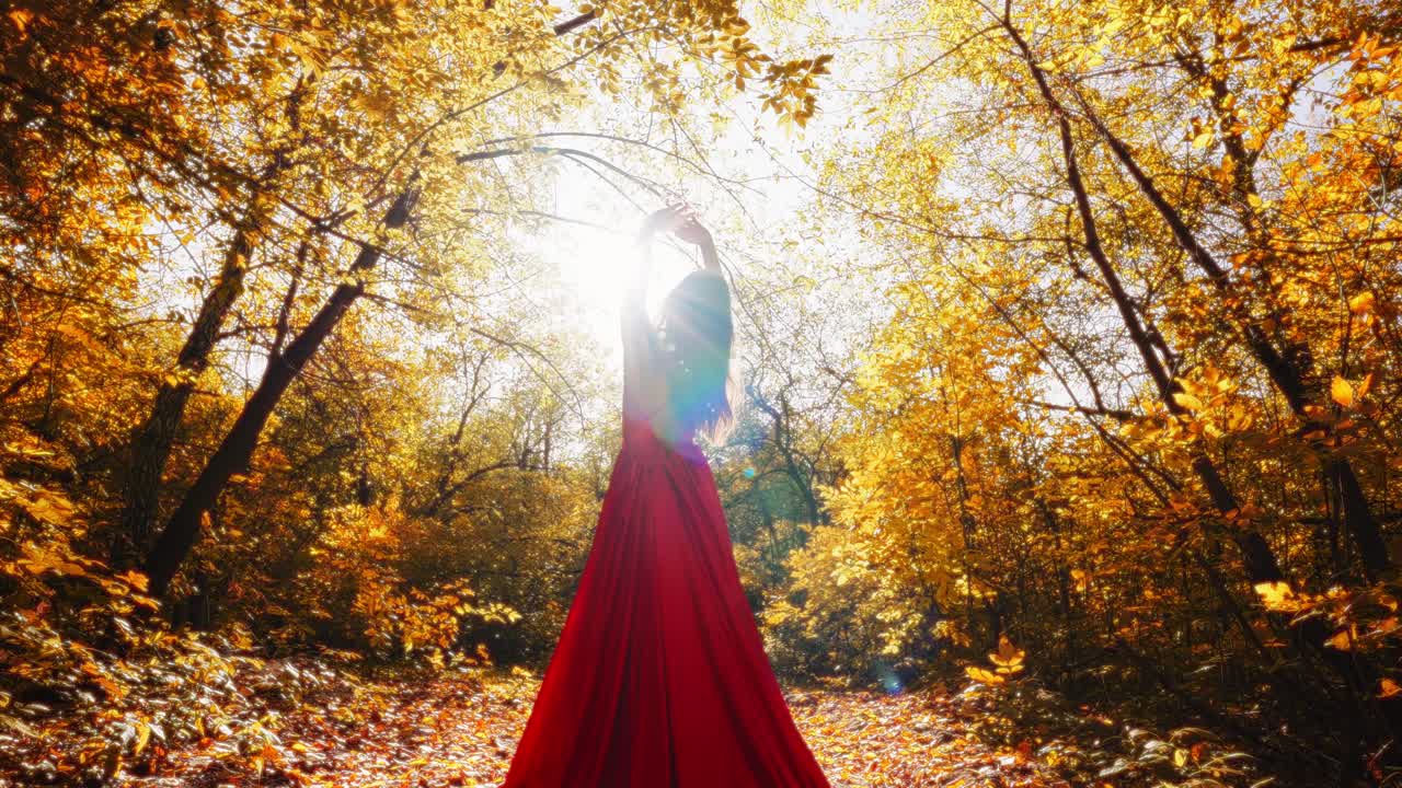 Una figura radiosa in un abito rosso svolazzante danza in un paesaggio autunnale dorato, catturando l'essenza della bellezza e della serenità della natura.