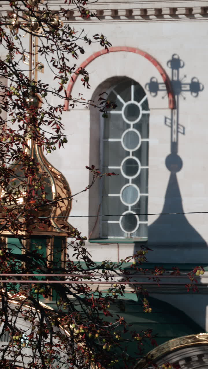 Beautiful architectural detail showing the shadow of a church cross projected on a wall with circular windows. Vertical