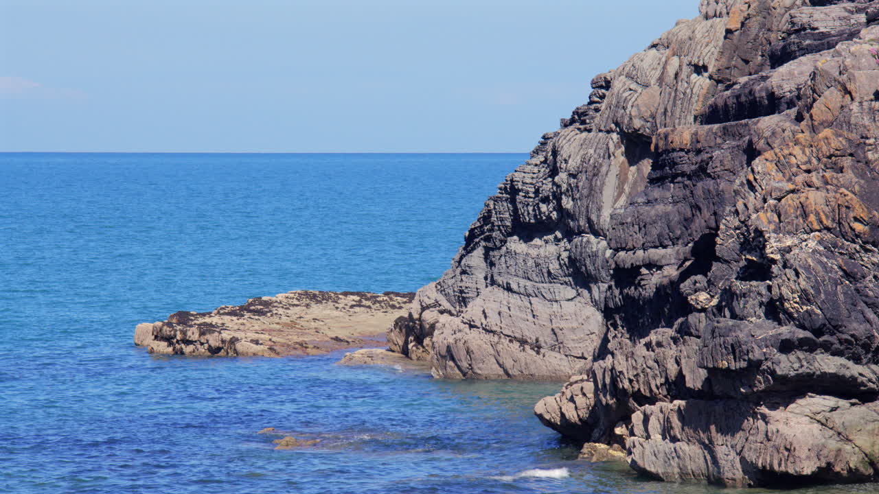 Inquadratura rivolta a nord-est delle formazioni rocciose con la bassa marea sulla spiaggia di Cwmtydu