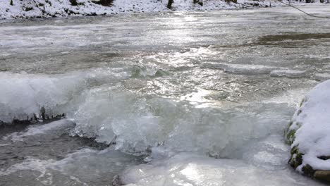 Slow-Motion-Water-flowing-in-the-frozen-Creek,-Ice-backlit