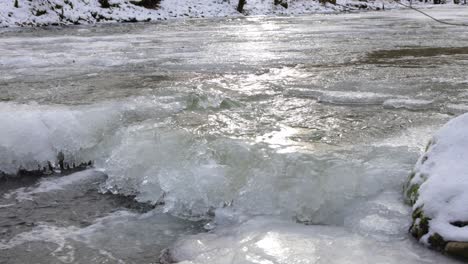 agua en cámara lenta que fluye en el arroyo congelado, retroiluminación de hielo