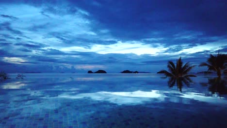 time lapse blue sunset with reflections by infinity pool