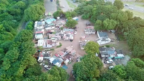 Vista-Aérea-De-Un-Campamento-De-Ocupantes-Ilegales-De-Chozas-Caseras-Junto-A-Un-Canal-Rodeado-De-Arbustos-En-El-Acantilado-En-Durban,-Sudáfrica