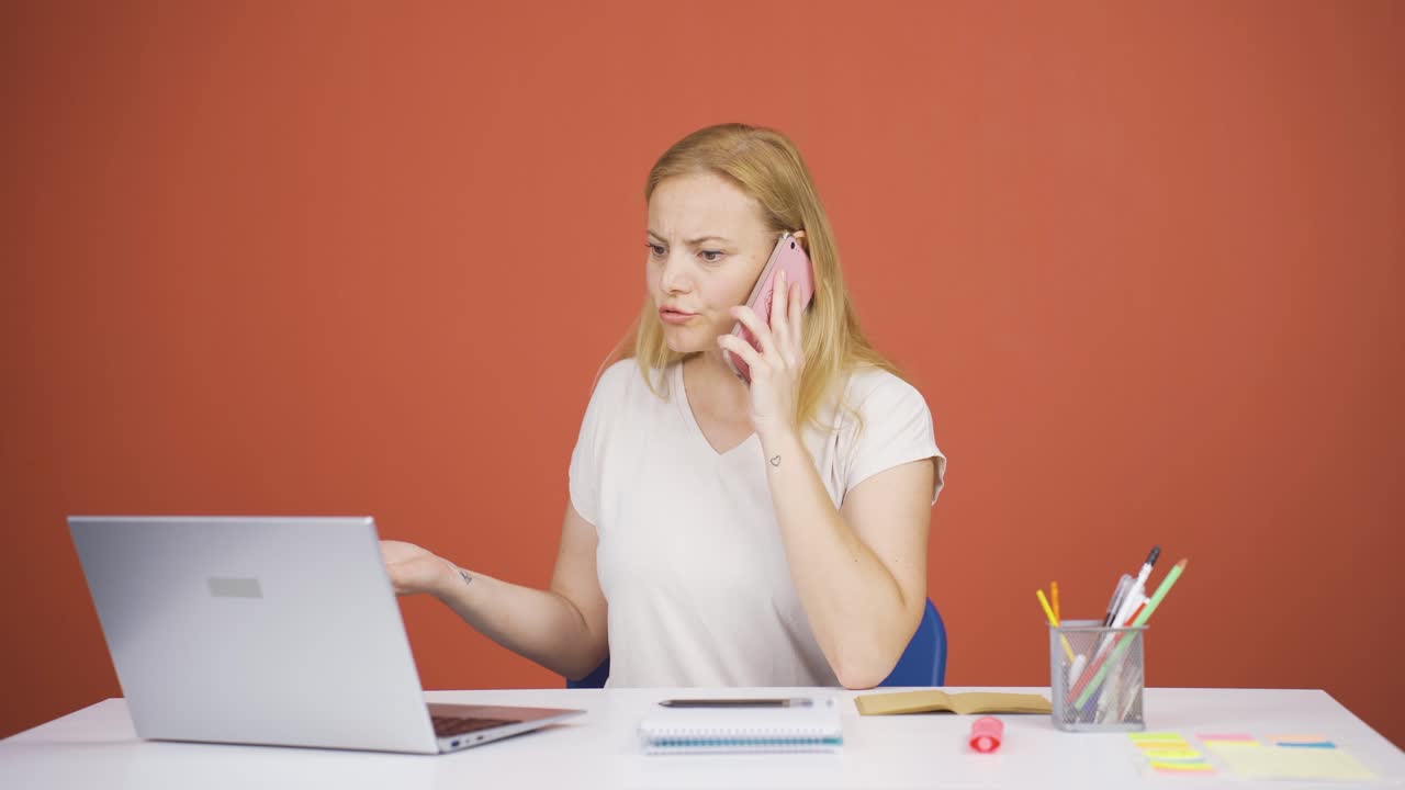 Woman using laptop nervously talking on the phone.