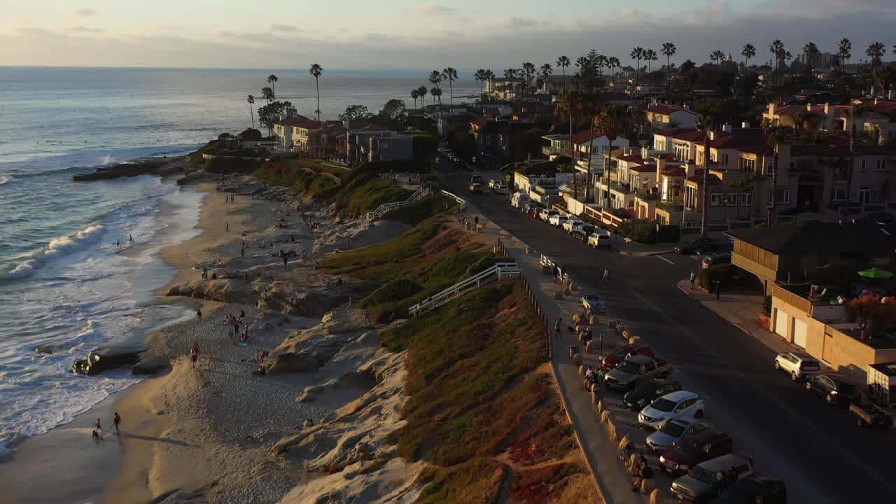 Drone che si allontana dalla spiaggia a La Jolla, San Diego, al tramonto, riprendendo persone che si godono la costa e le viste sull'oceano.