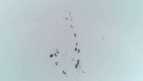 Toma-Aérea-De-Drones-De-Excursionistas-Profesionales-De-Montaña-Caminando-Cuesta-Arriba-En-La-Nieve-Por-Un-Frío-Sendero-De-Montaña-Nevado