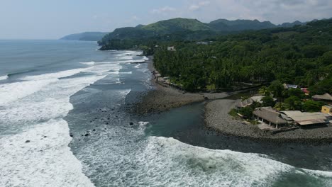 Aerial-view-moving-forward-shot,-scenic-view,-waves-splashing-on-the-rocky-shore-of-the-bitcoin-beach-in-El-Salvador-Mexico