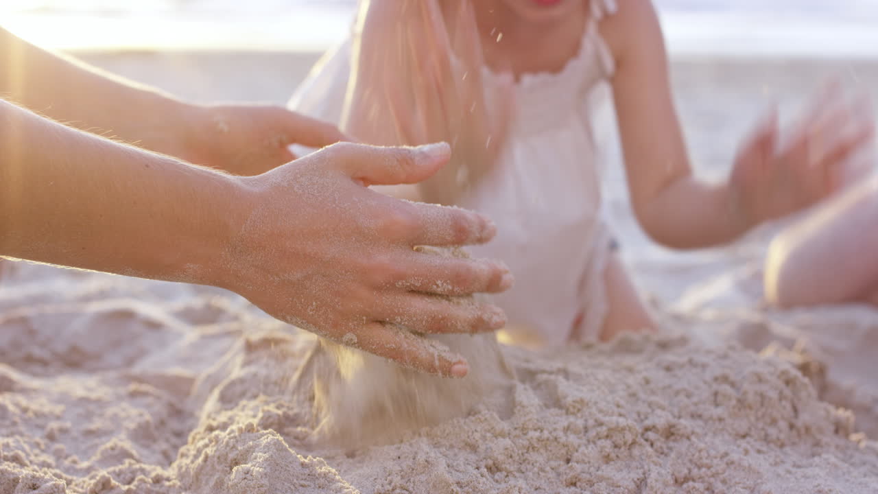 해가 지는 동안 해변에서 모래 성을 짓는 행복한 가족