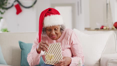 happy senior african american woman wearing santa claus hat, having video call at christmas