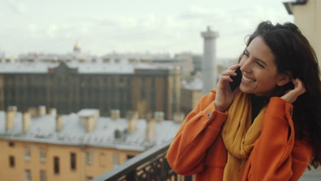 mujer caminando en la terraza del techo y hablando por teléfono