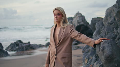 fashion model posing ocean coast in elegant suit. attractive blonde at sea waves