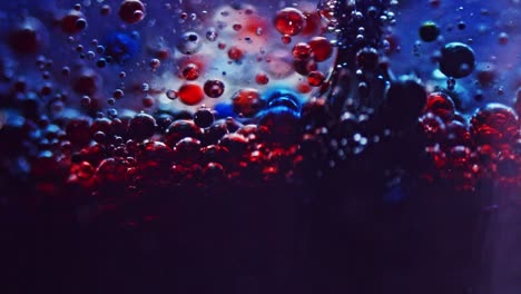 macro shot of dark blue ink bubbles rising from bottom of a glass of water