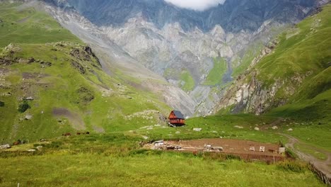 an aerial approaching a small cabin the high high mountains of the republic of georgia