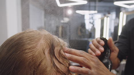 barbero mojando el cabello del cliente antes de cortarlo