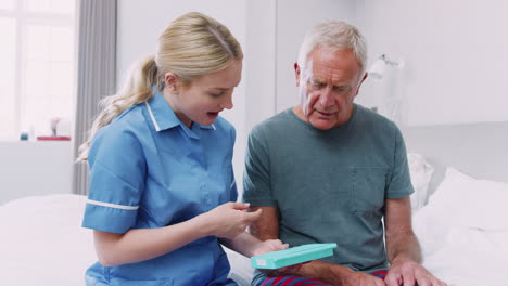 nurse helping senior man to organize medication on home visit