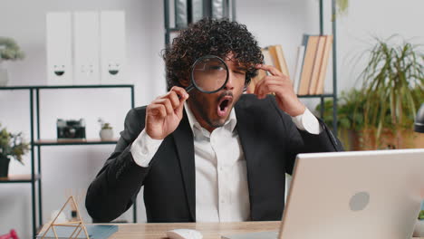 business man holding magnifying glass near face looking with big zoomed eye searching analysing