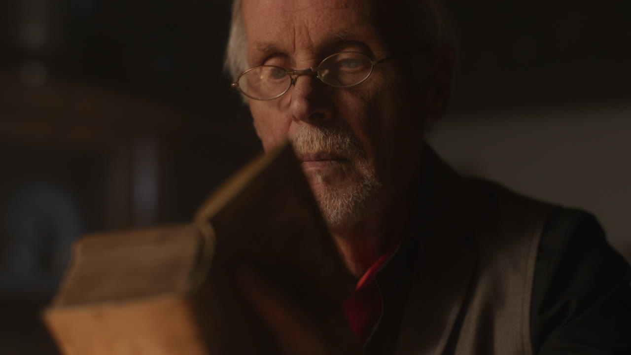 Old passionate man read a book in his office at night