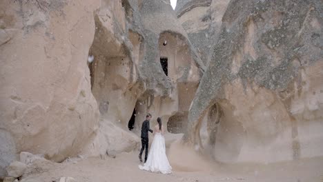 una pareja caminando por las nevadas cuevas de capadocia.