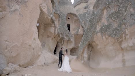 couple walking through snowy cappadocian caves