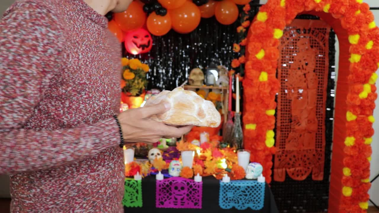poniendo pan como ofrenda en el decorado día mexicano del altar de los muertos