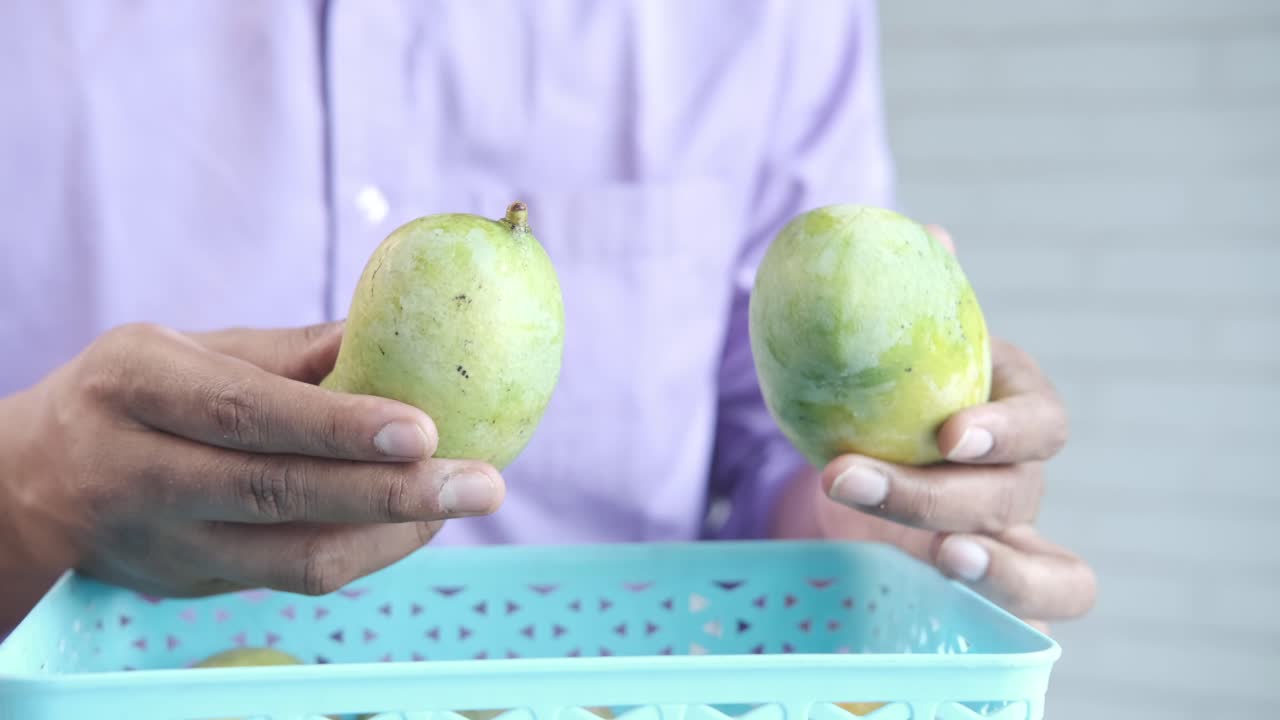 persona con mangos en una canasta
