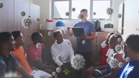 animation of virus cells over diverse group of male football players with coach in changing room