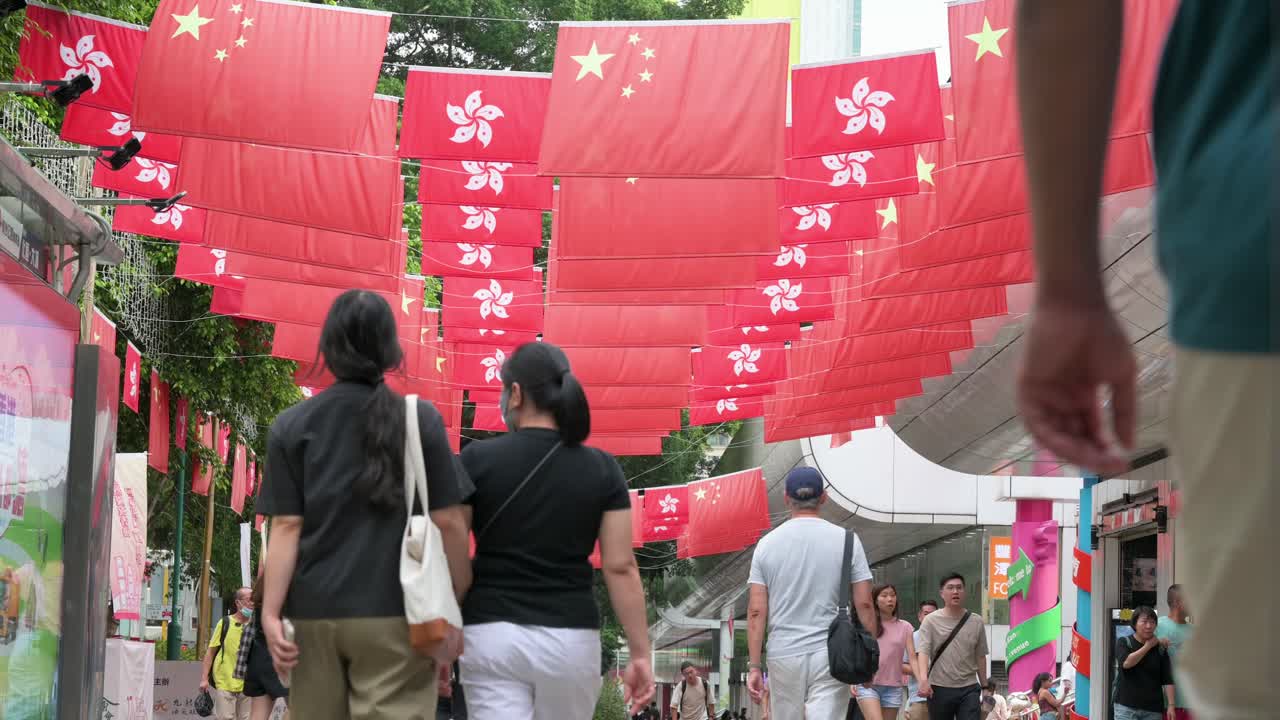 People Walking Down a Street Decorated with Hong Kong and Chinese Flags