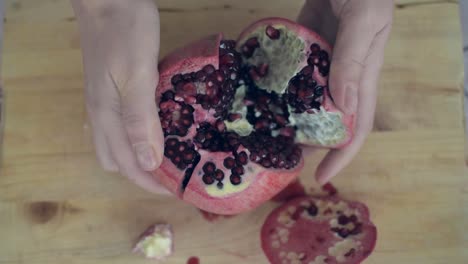 opening a sliced pomegranate with hands, easily