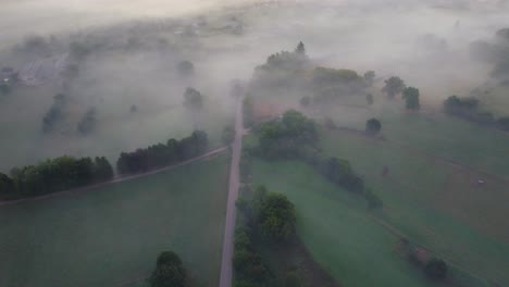 aerial view of a foggy landscape with fields and a road