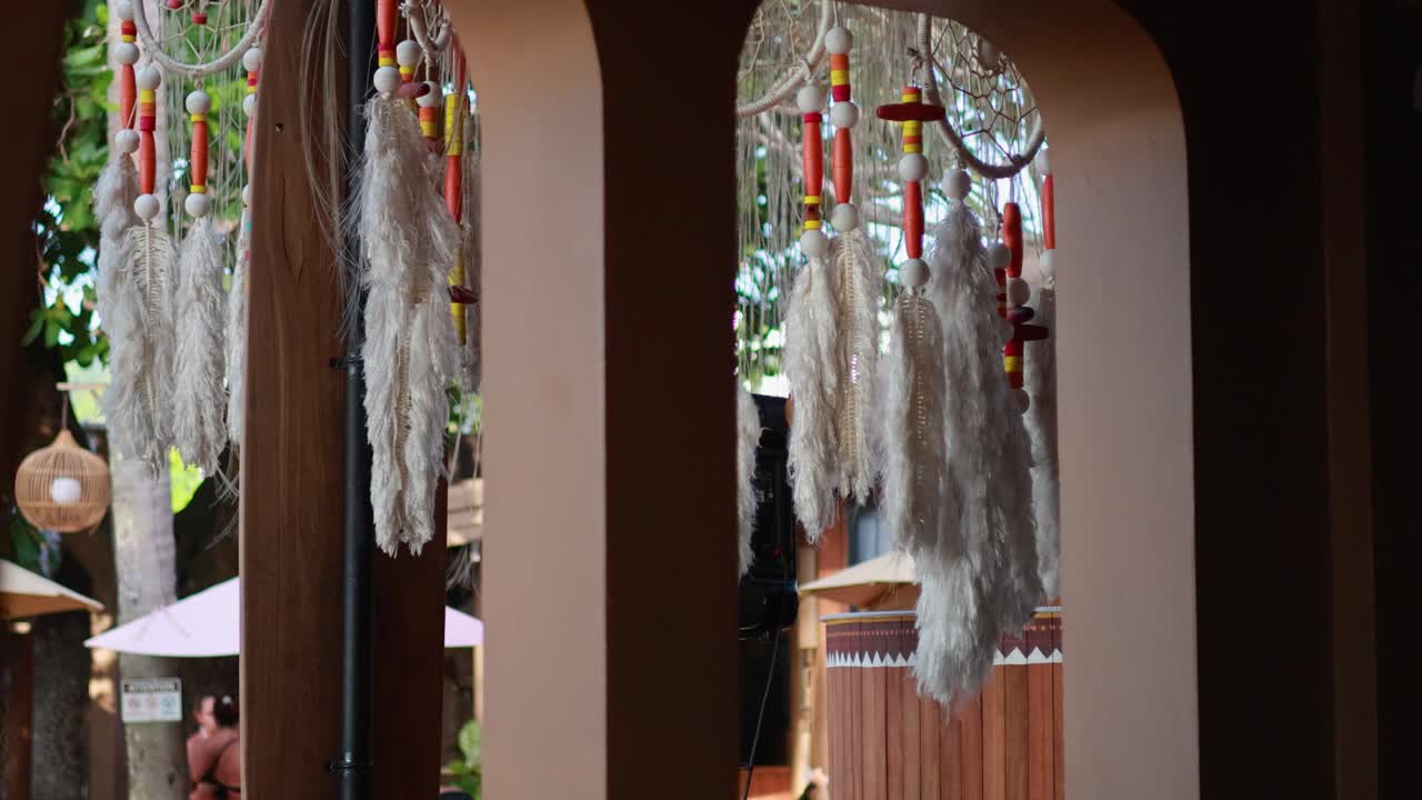 Feathers and shells sway gently in a Phuket archway, creating a serene and cultural ambiance