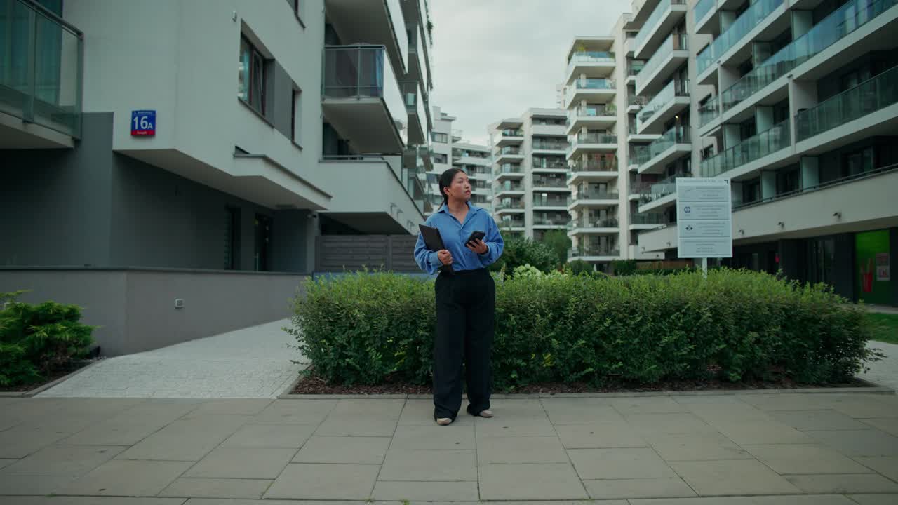Kvinde, der står foran en lejlighedsbygning