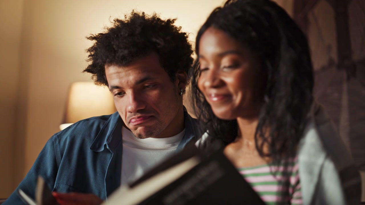 Enamoured couple reading home enjoying calm domestic leisure apartment closeup