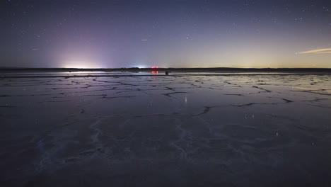 timelapse of moonset and stars in a mirror like lake