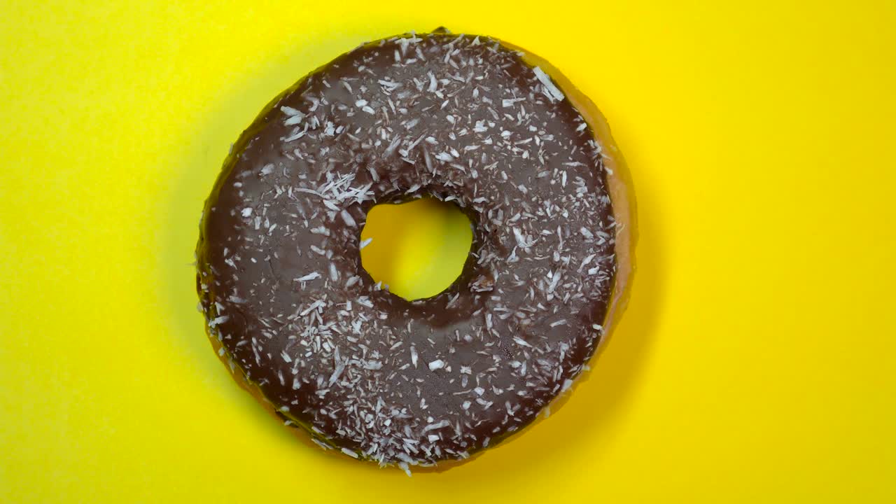 deliciosa rosquilla de chocolate dulce girando rápidamente en un plato. vista superior. fondo amarillo.