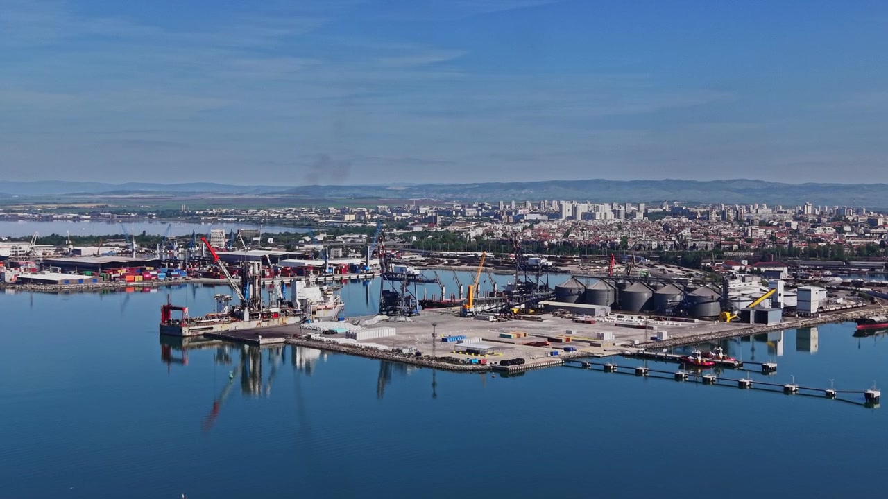 Vista del porto con gru e barche in una zona portuale trafficata vicino a una città.