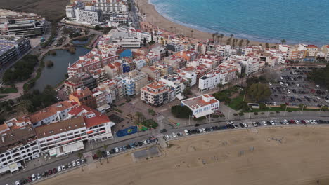 wide aerial shows peniscola town and playa sur beach with castell de peniscola behind