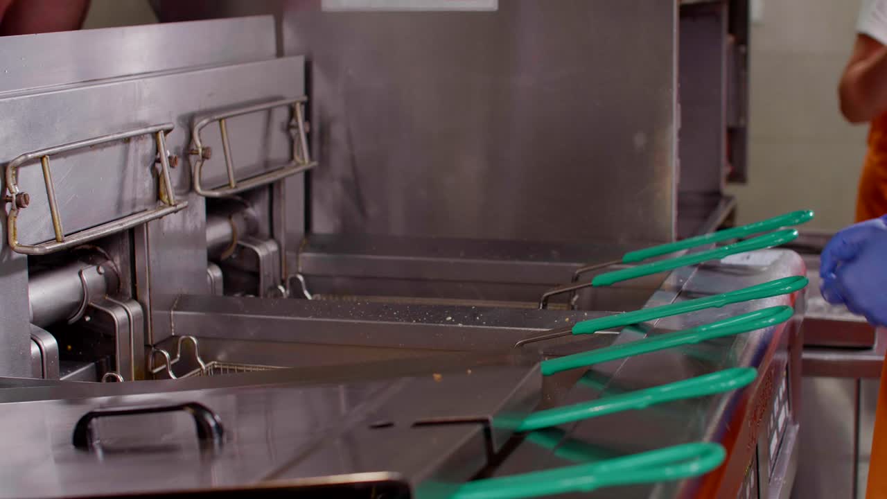 la cesta freidora de patatas fritas se retira del aceite en la cocina de comida rápida