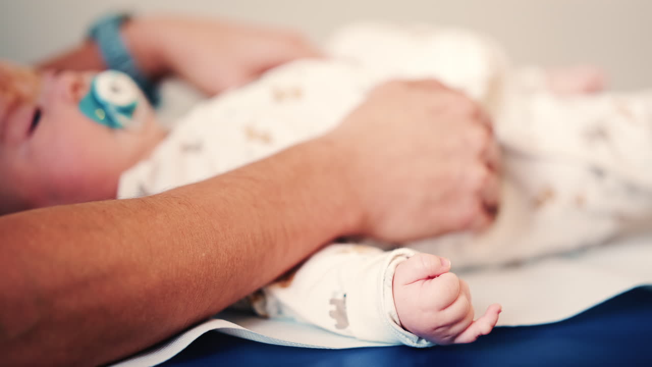 Esame di un neonato su un fasciatoio mentre è tranquillo con un succhietto