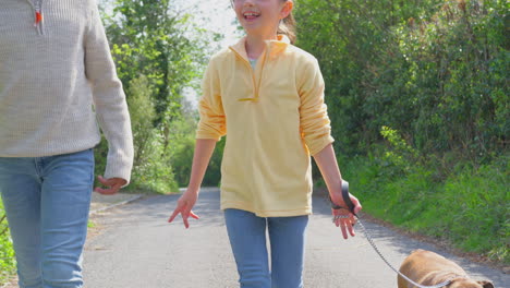 two children walking pet french bulldog dog along country road