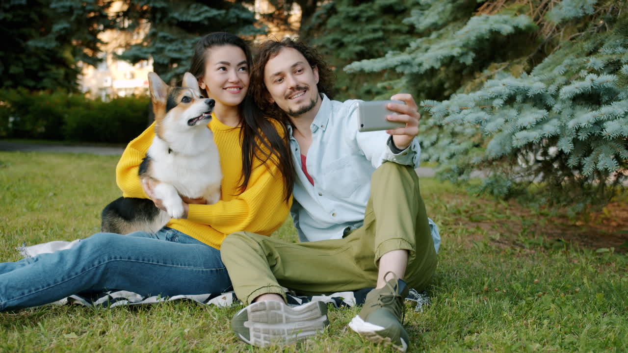 Couple taking a selfie with their dog in a park