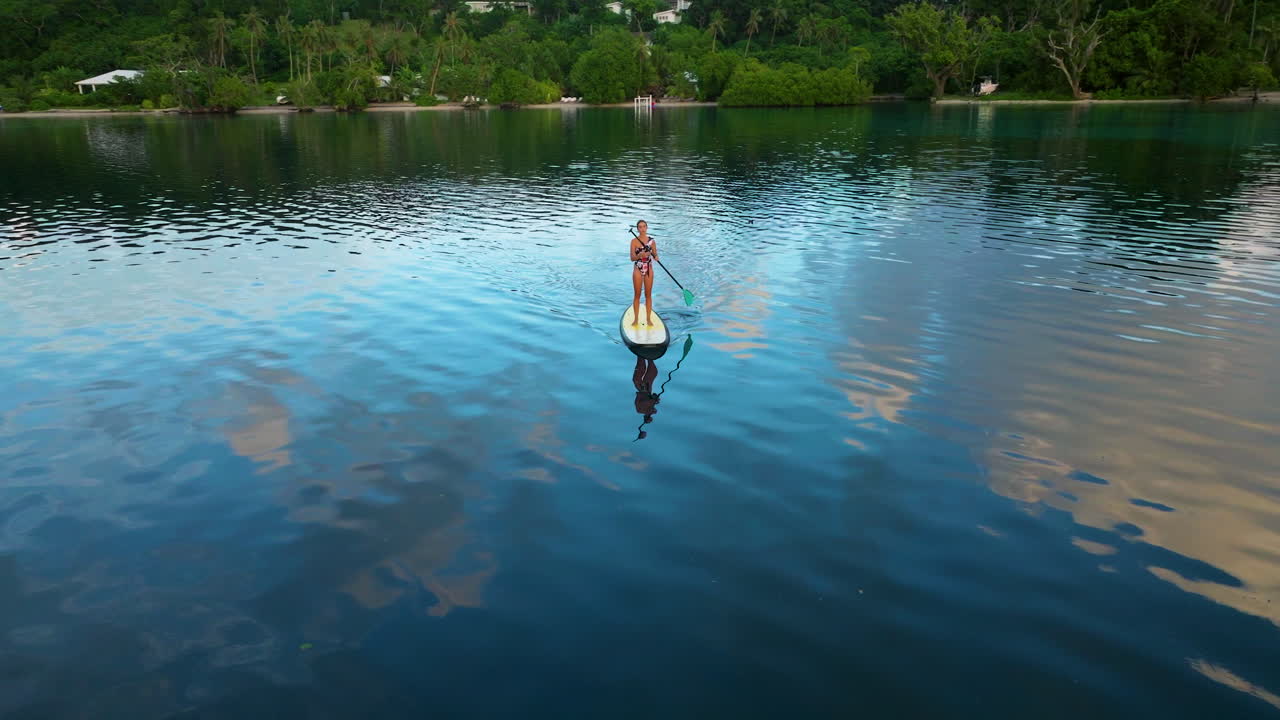 una turista femenina en un stand-up paddle en la impresionante isla de moso, en el norte de efate, vanuatu