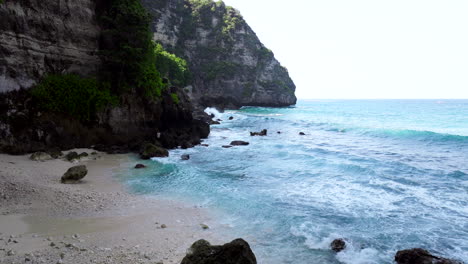 In-shadow-of-rock,-Balinese-fisherman-at-shore-attempting-to-catch-food